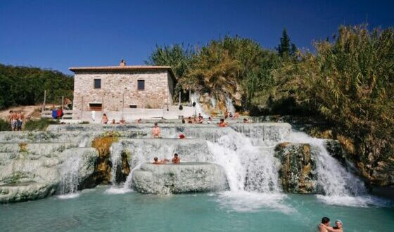 Grupo de personas disfrutando de una fuente termal en Saturnia, Toscana, Italia.
